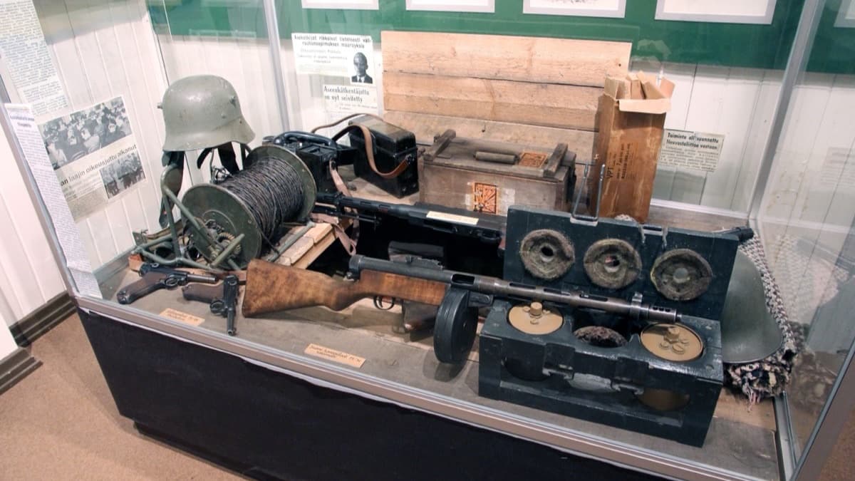 Museorepliikka SA-leimatuista sotilasvarusteista asekätkössä lattian alla